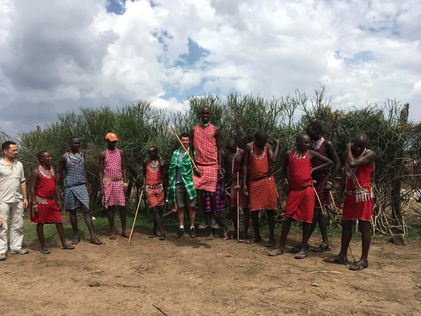 People standing outdoors beside a rustic enclosure